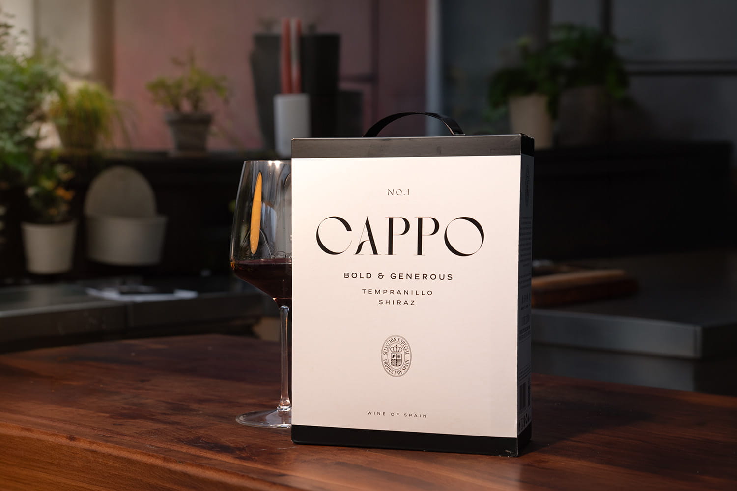No.1 Cappo Tempranillo/Shiraz i box bredvid ett glas rödvin på en köksbänk
