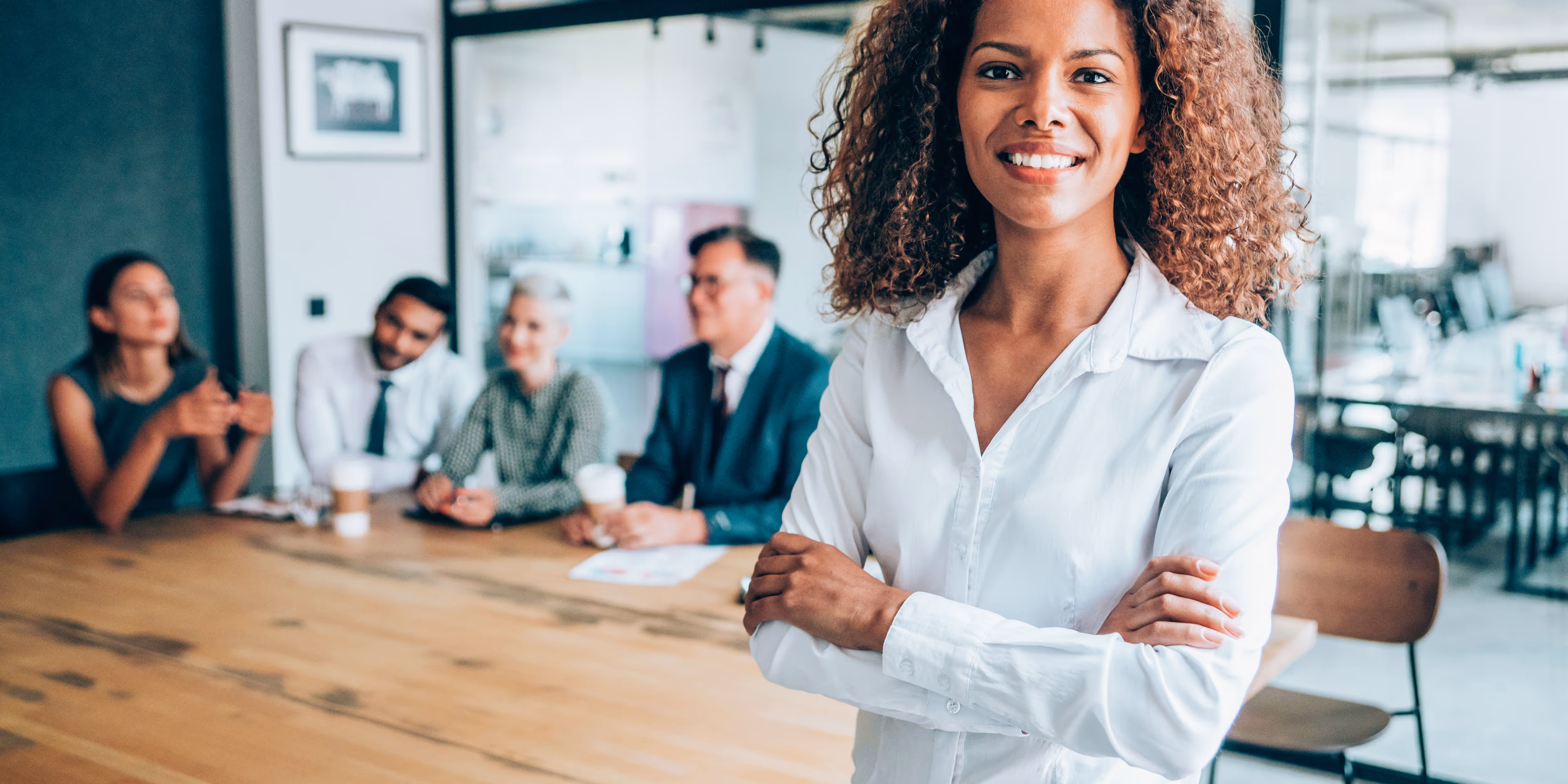 First Technology business woman smiling at camera with co workers in the background