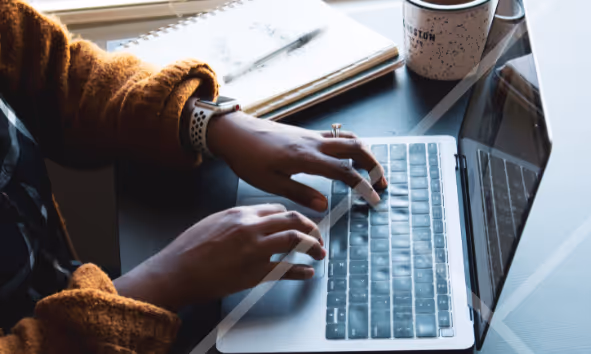 Close-up of hands typing on a laptop