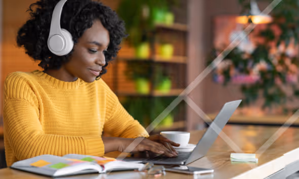 Woman weaing headphones typing a laptop - First Technology Cyber Security Solutions