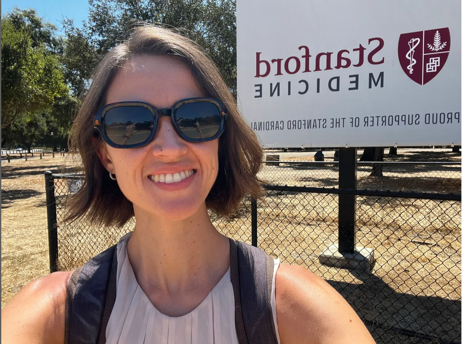 Two medical professionals in scrubs and protective gear are standing near a computer monitor displaying a surgical procedure, with additional screens and equipment visible in the background.