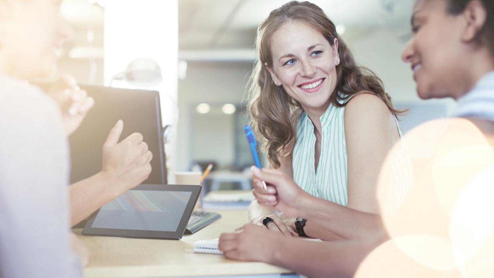 Smiling colleagues collaborating in a bright, modern office environment, embodying the innovative and team-oriented workspace at The MacArthur's Collaboration Hub.