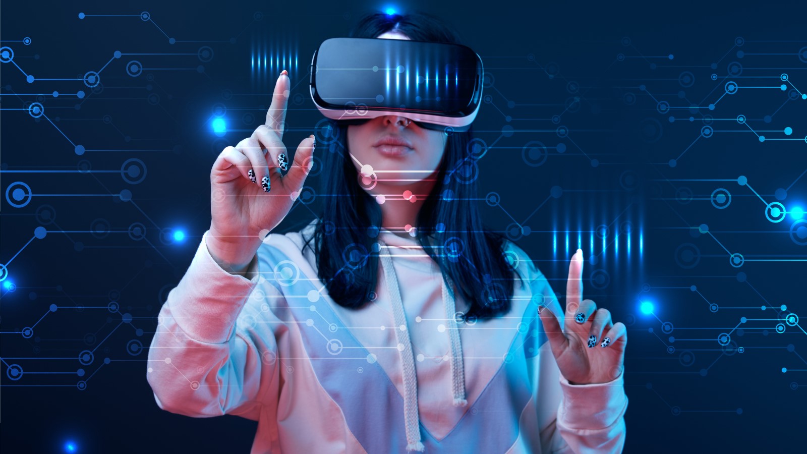 A young woman wearing a virtual reality headset, immersed in a digital experience, points with her fingers toward a luminous cybernetic graphic that floats in front of her against a dark backdrop. The scene captures the convergence of technology and exper
