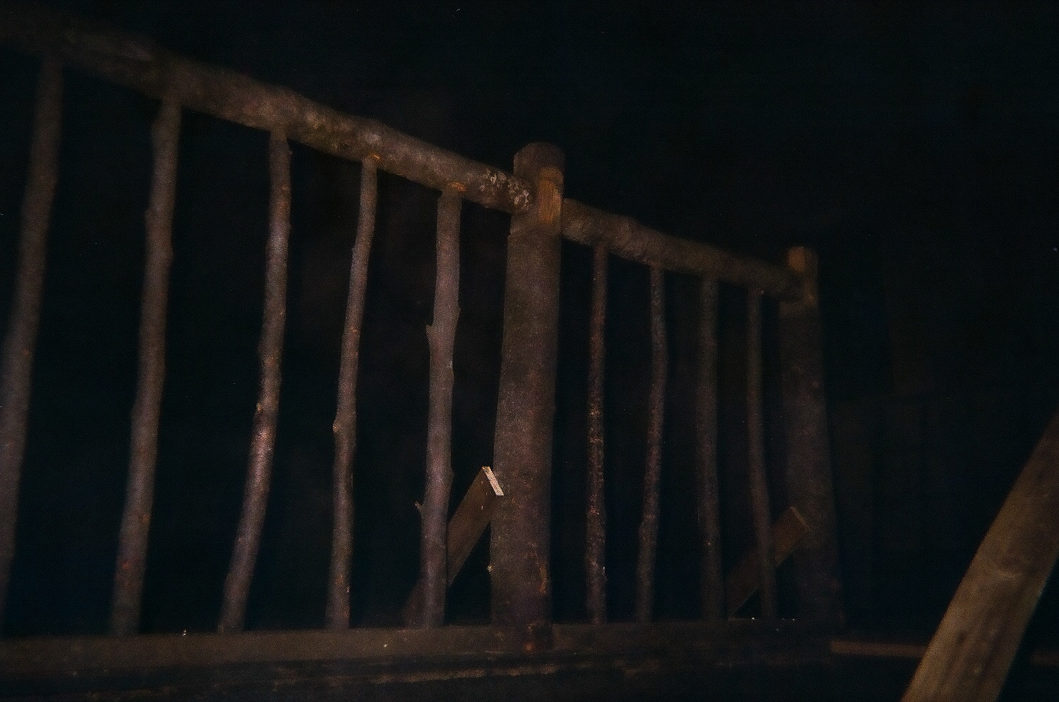 Rustic wooden railing made of uneven logs in a dark setting.