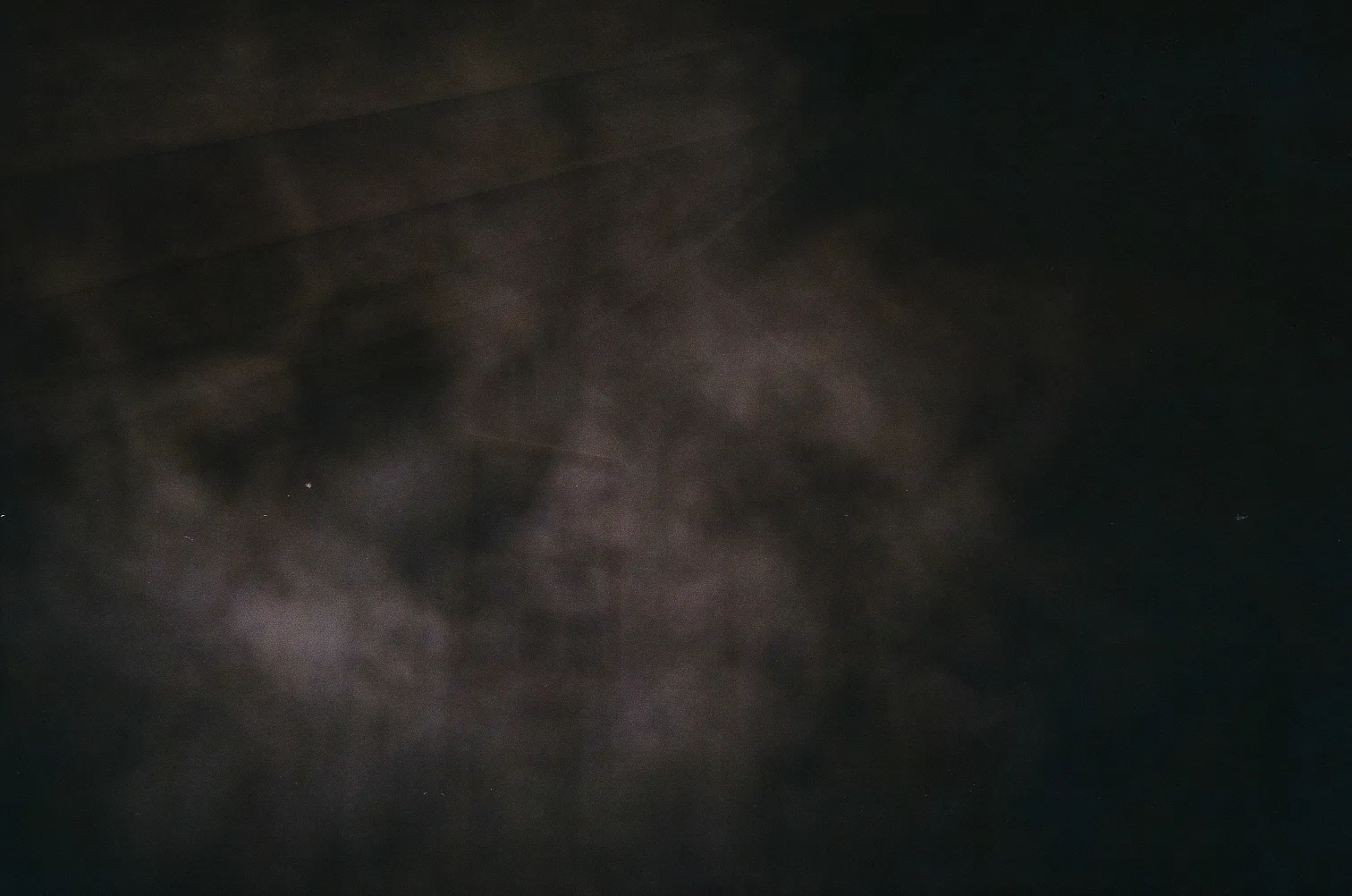 Dark background with faint abstract light patterns resembling smoke or mist.