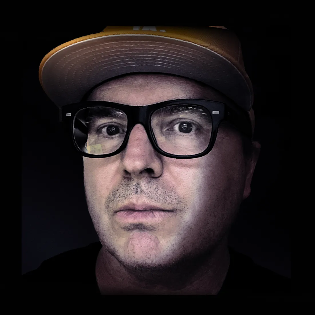 Close-up dramatic portrait of Markus Hagen wearing black-framed glasses, with subtle color streak overlay elements.