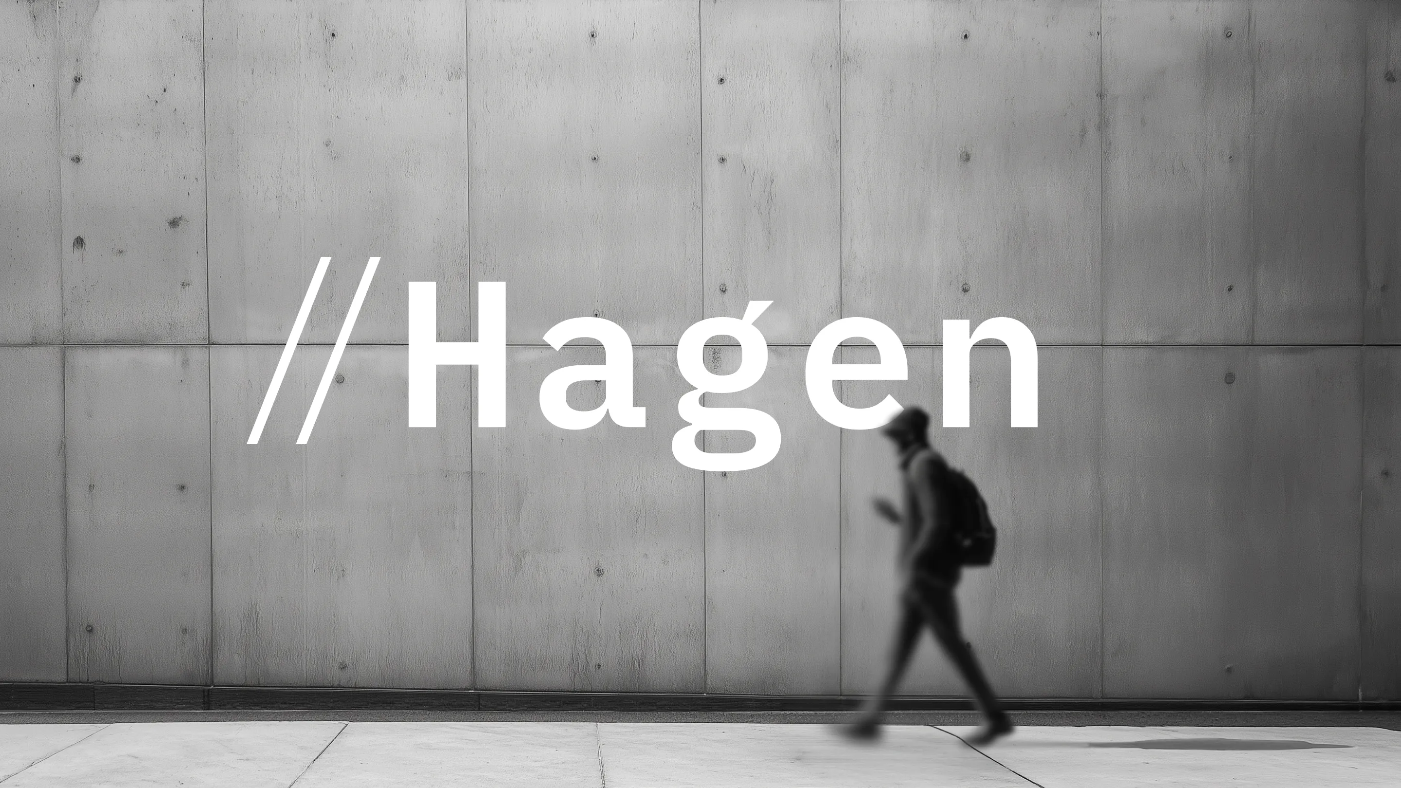 A black and white architectural photograph of a brutalist concrete building. Red technical construction grid lines are overlaid on the image, intersecting with a white 'Hagen' logo in the center.