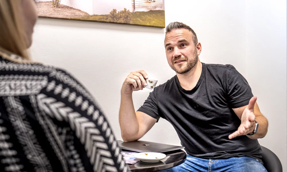 Muž se šálkem kávy mluví na poradě s kolegou