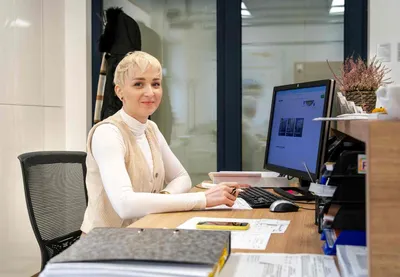 Mladá žena sedí za počítačem v prodejně oken
