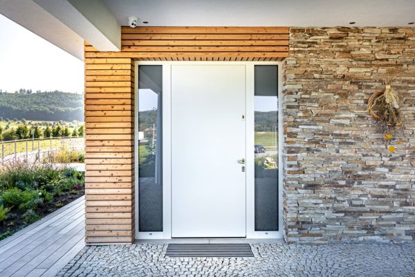 Bílé hliníkové vchodové dveře s bočními světlíky v moderním domě s dřevěnou fasádou