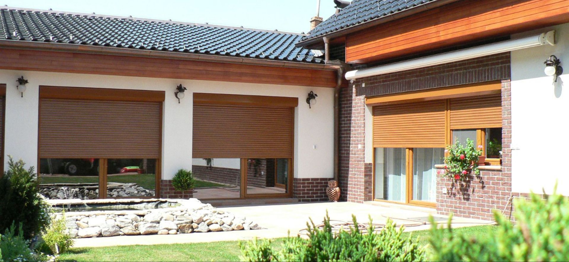 Rodinný dům s velkými okny a částečně zataženými roletami s dřevěném dekoru