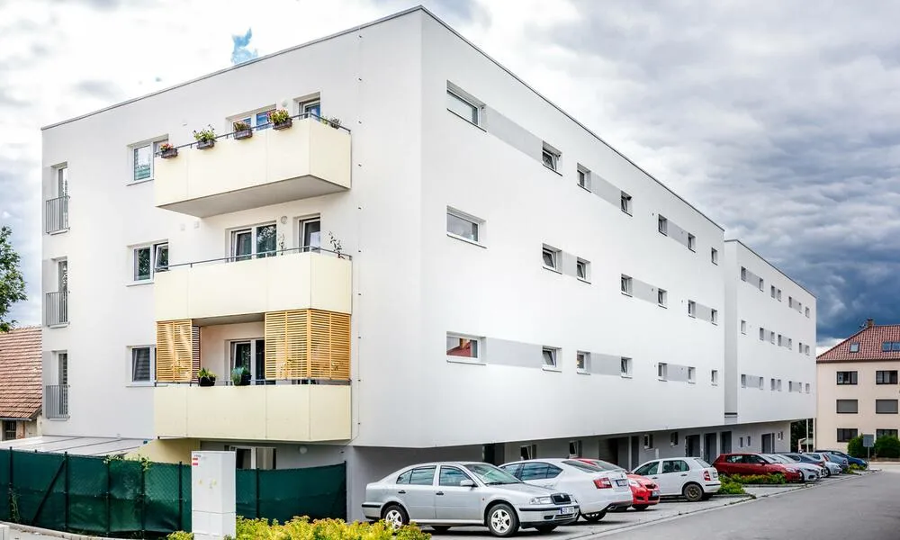 Čtyřpodlažní bytový dům s plastovými okny a světle žlutými balkony