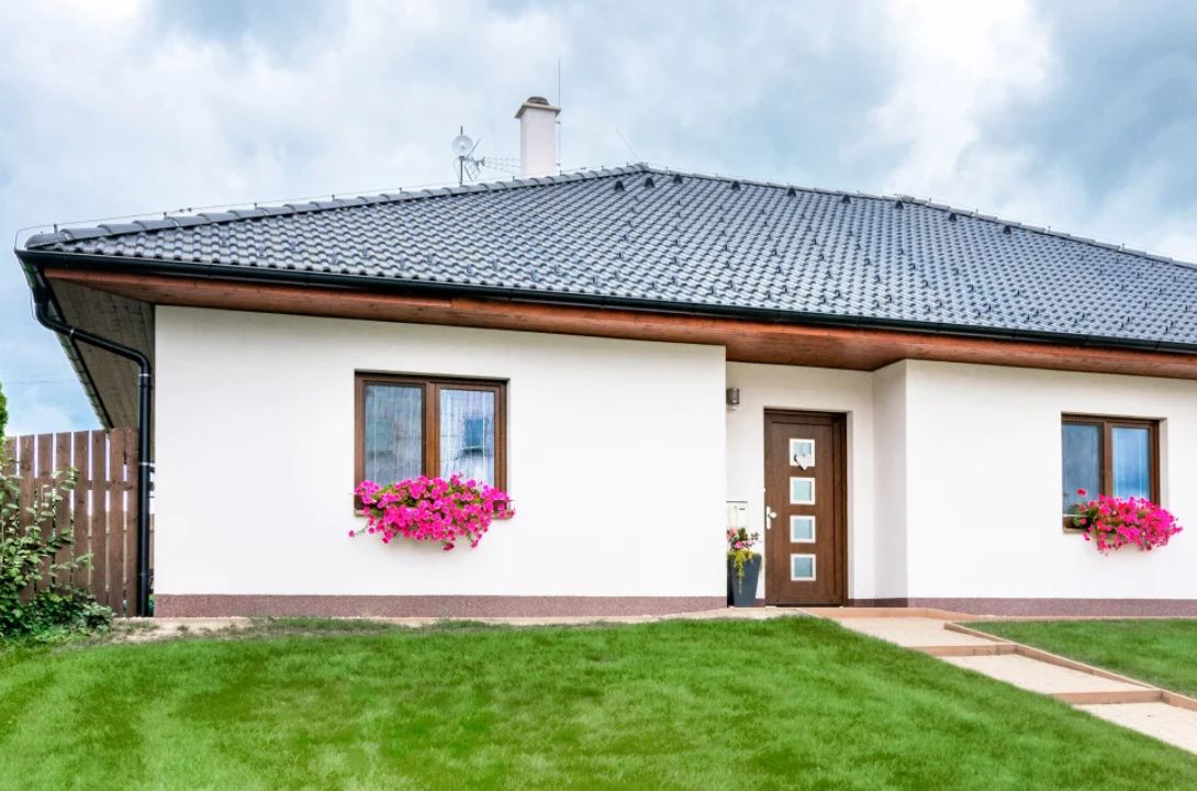 Hnědé vchodové dveře a okna v domě s bílou fasádou