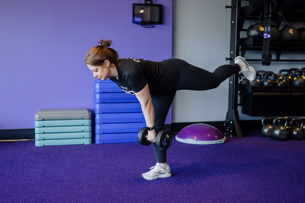 Anytime Fitness Coach demonstrating a single-leg deadlift with a dumbbell.