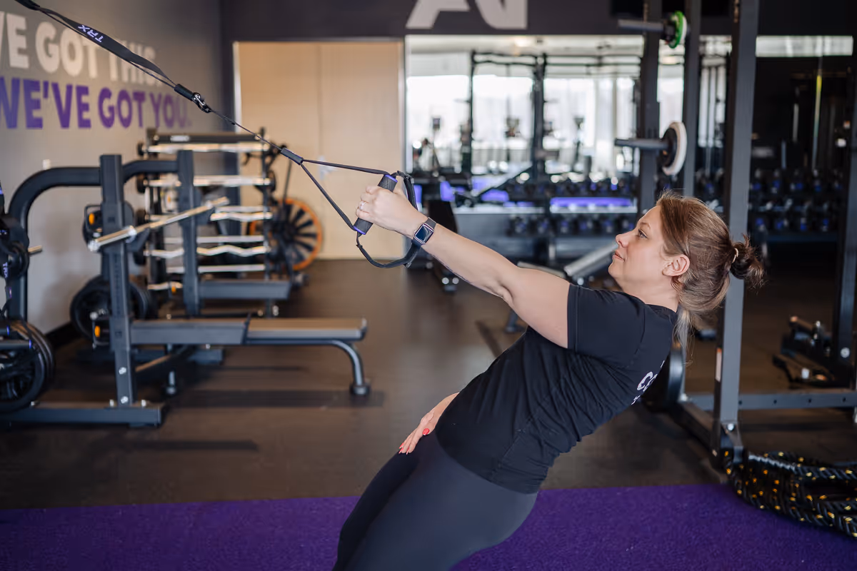Anytime Fitness Coach using a TRX strap to perform a single-arm row.