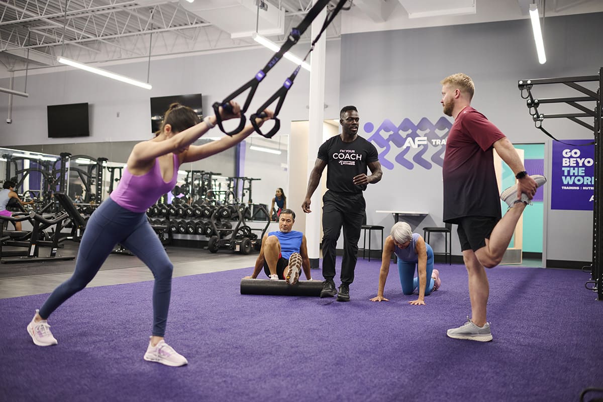 Anytime Fitness Coach leading a group training session in a gym.