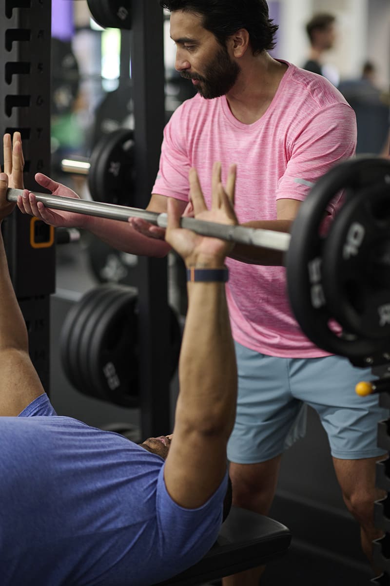 Spotter helping a lifter complete a bench press rep.
