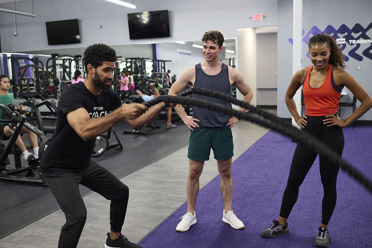 Anytime Fitness Coach demonstrating how to use battle ropes during a group training session.