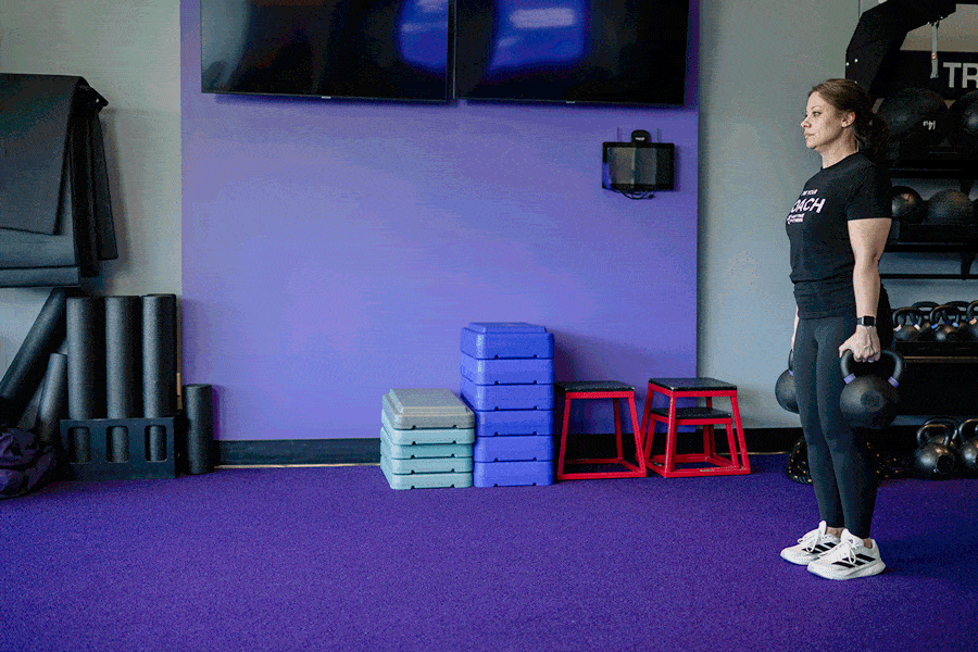 Anytime Fitness Coach demonstrating farmer carries.