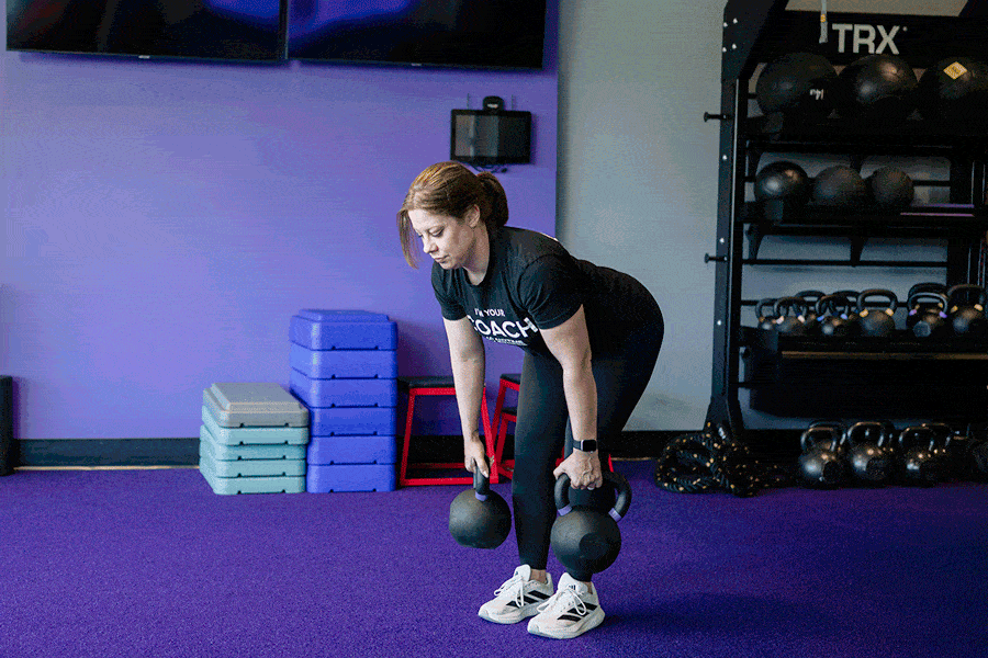 Anytime Fitness Coach demonstrating how to do a suitcase deadlift.