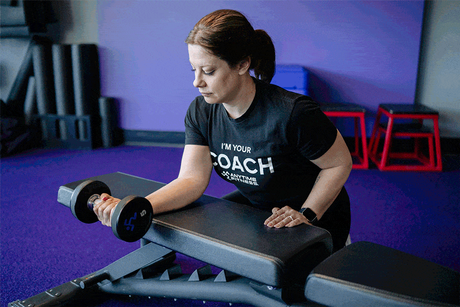Anytime Fitness Coach demonstrating how to do a wrist curl with a bench.