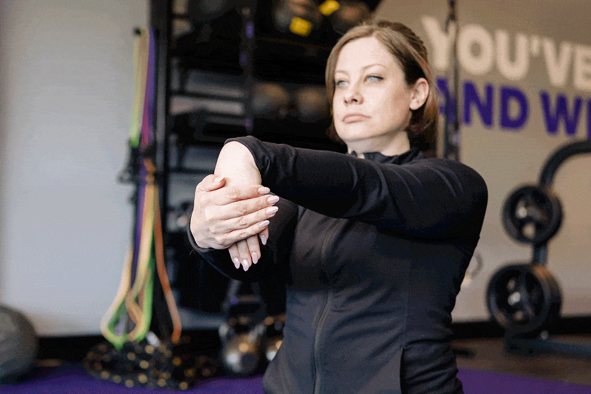 Anytime Fitness Coach demonstrating how to do a wrist flexion stretch.