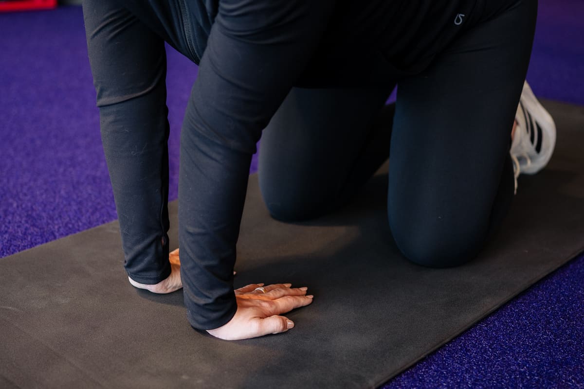 Anytime Fitness Coach demonstrating how to do a wrist extension stretch.