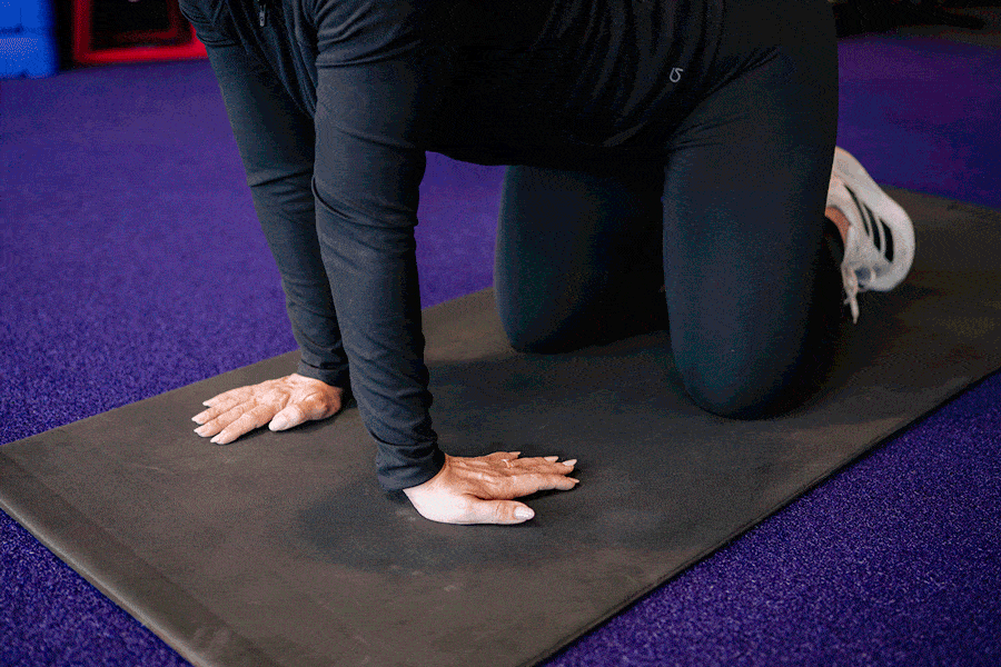 Anytime Fitness Coach demonstrating a wrist mobility drill.