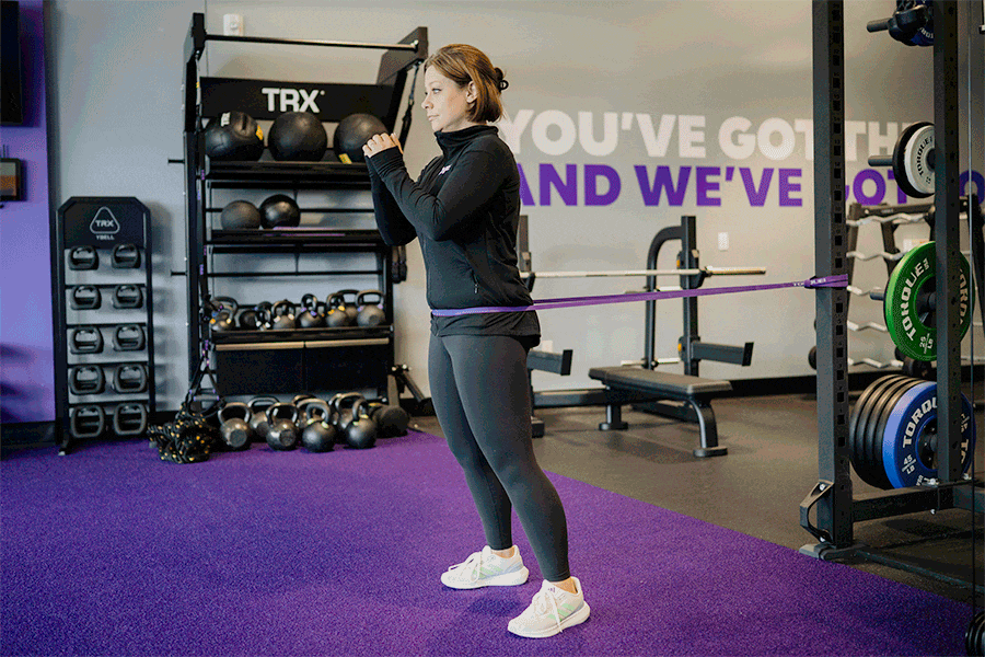 Anytime Fitness Coach demonstrating how to do a band-resisted hip hinge activation drill.
