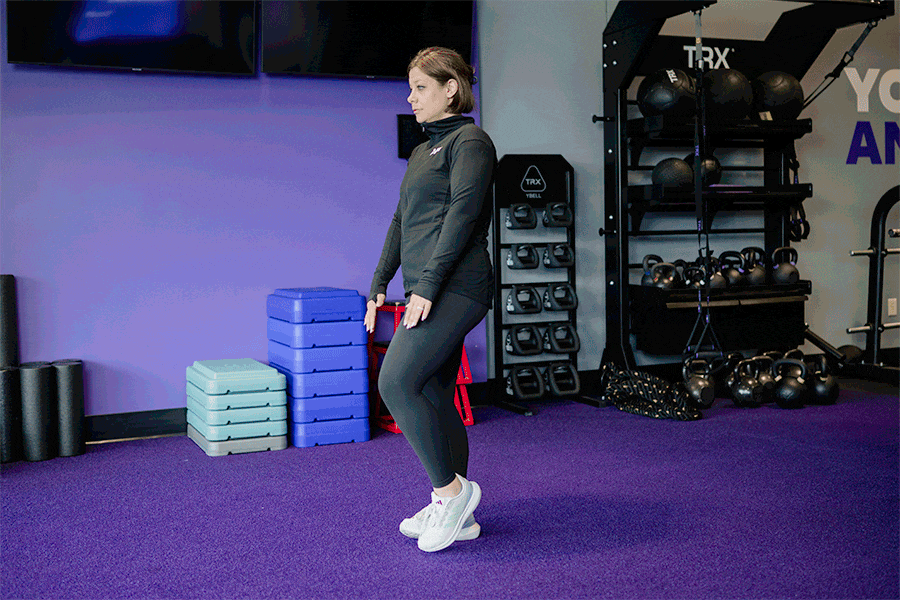 Anytime Fitness Coach demonstrating how to do a single-leg reach.