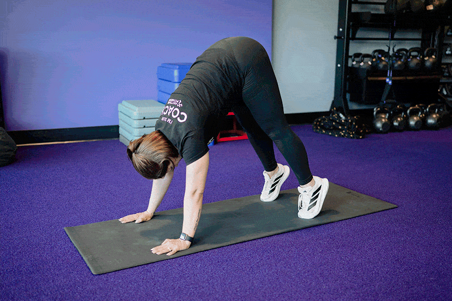 Anytime Fitness Coach demonstrating a pike push-up.