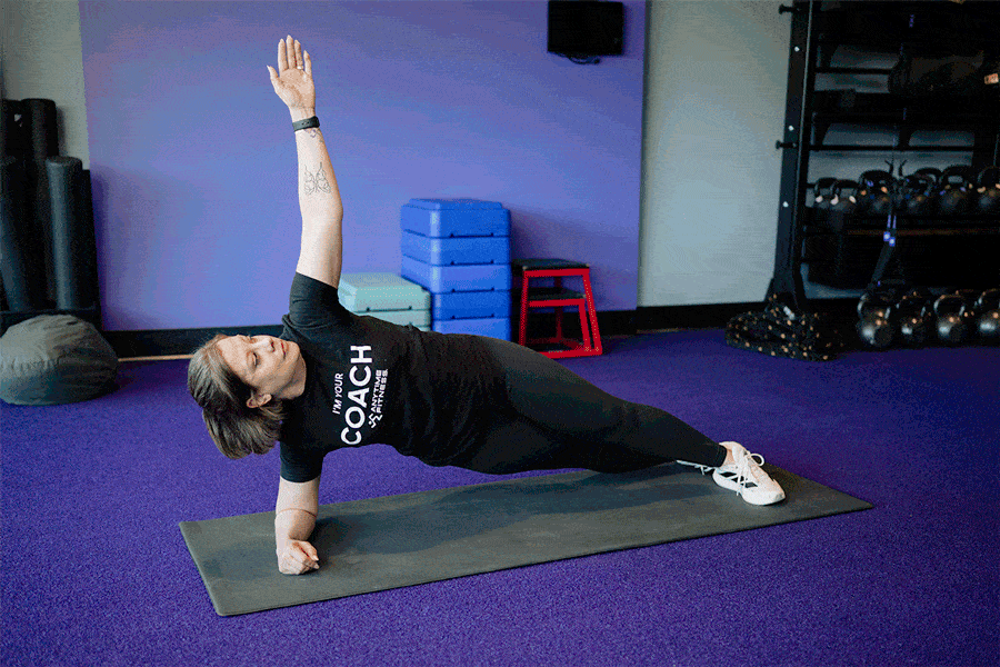 Anytime Fitness Coach demonstrating a side plank rotation.