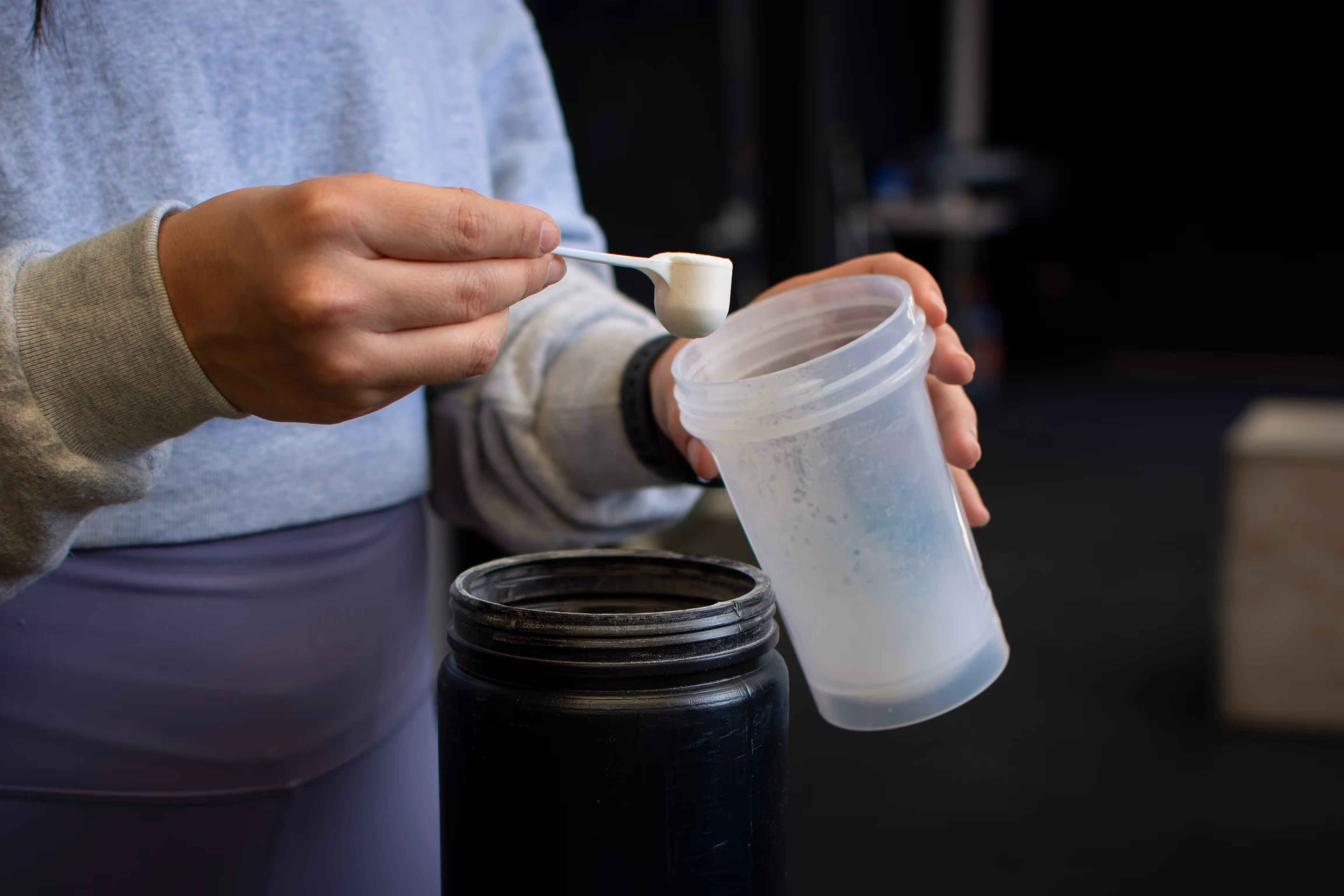 Woman adding a creatine supplement to a bottle.
