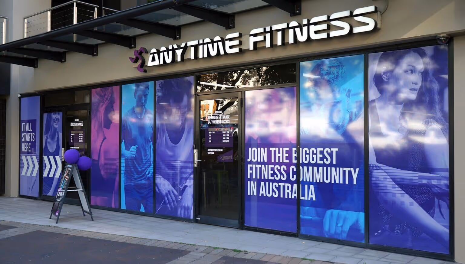 Exterior of an Anytime Fitness gym with large purple window graphics and text reading “Join the biggest fitness community in Australia.”