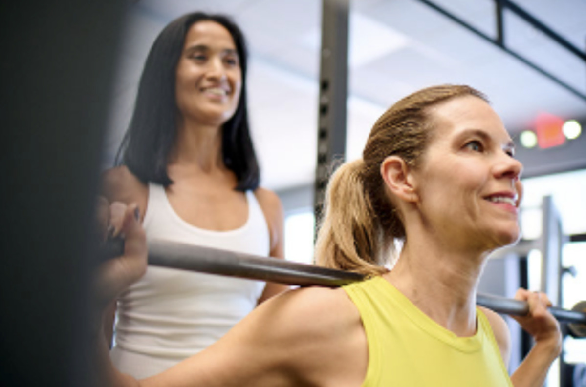 Two women are doing weight lifting in an Anytime Fitness gym.