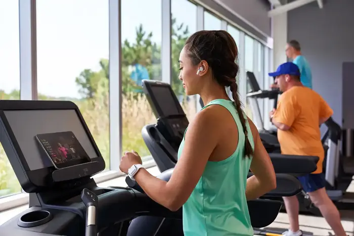Woman exercising on treadmill at a gym with others in the background