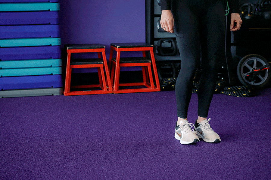 Anytime Fitness Coach demonstrating lateral walking, a strength and balance exercise.