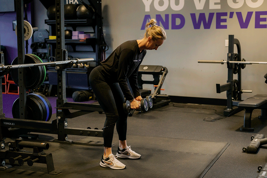Anytime Fitness Coach demonstrating a bent-over rear delt fly.