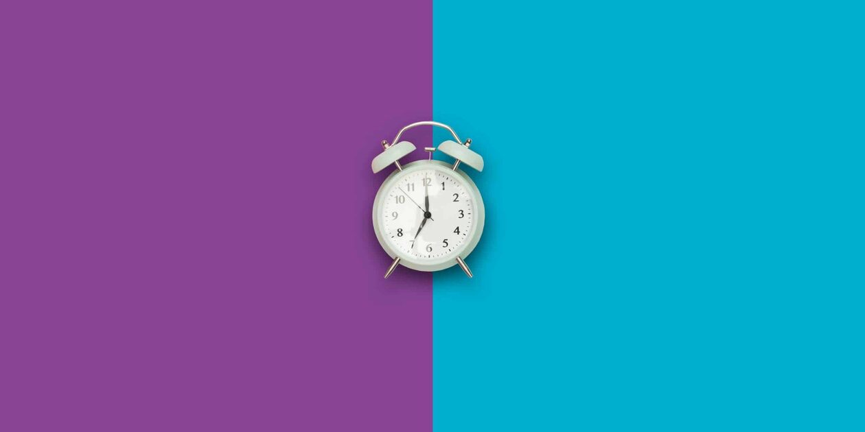 A mint green vintage alarm clock centered on a split purple and blue background, illustrating the best time to visit the gym for a workout.
