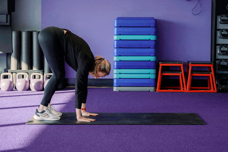 Anytime Fitness Coach demonstrating an inchworm walkout, part of a mobility strength training workout.