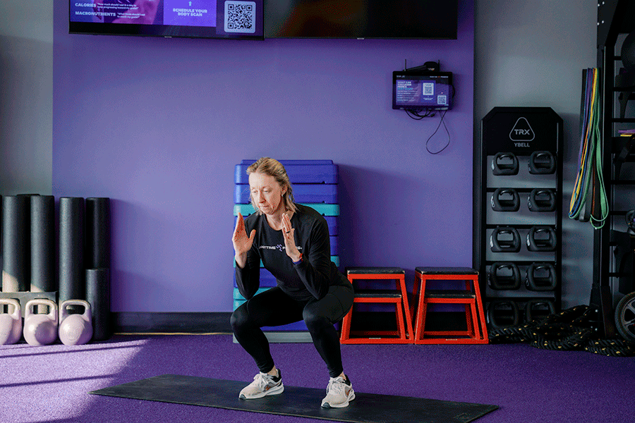 Anytime Fitness Coach demonstrating a squat to calf raise, part of a mobility strength training workout.