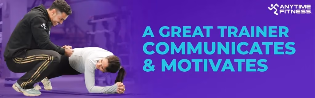 Anytime Fitness promotional banner stating "A GREAT TRAINER COMMUNICATES & MOTIVATES." The image shows a male trainer crouching down to encourage a woman while she performs a plank exercise on a gym mat.