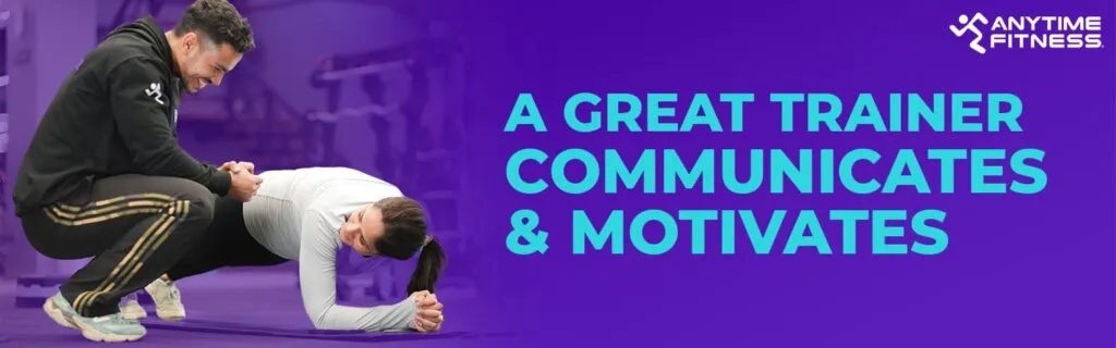 Anytime Fitness promotional banner stating "A GREAT TRAINER COMMUNICATES & MOTIVATES." The image shows a male trainer crouching down to encourage a woman while she performs a plank exercise on a gym mat.