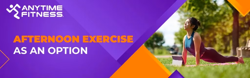 A promotional banner with the text "AFTERNOON EXERCISE AS AN OPTION." The image features a woman practicing an upward-facing dog yoga pose on a pink mat in a sunlit park, using a tablet for guidance.