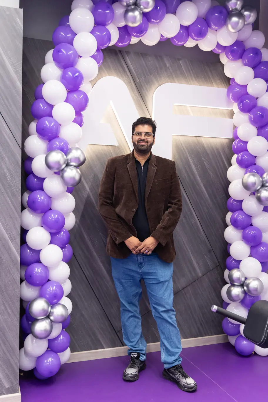 Salil Ghate, Anytime Fitness franchise owner in Mumbai, standing inside an AF gym beneath a purple and white balloon arch.