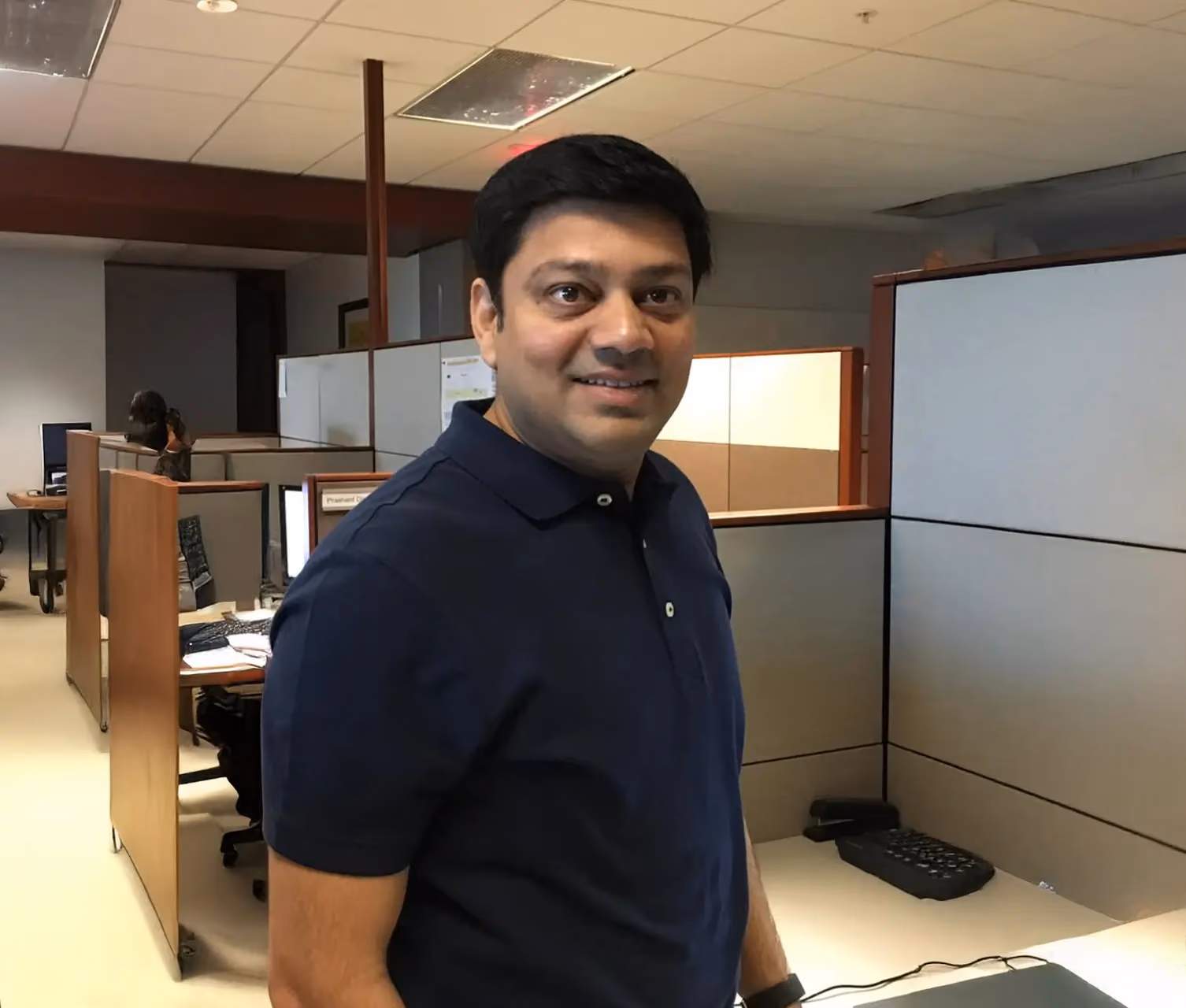 Madhu Mandava, Anytime Fitness multi-club owner from Telangana, standing in an office workspace.