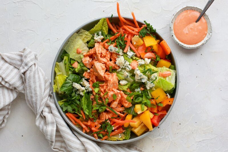 Creamy buffalo chicken salad bowl, a high-fiber, high-protein meal with carrots, peppers, lettuce, chicken, and blue cheese.