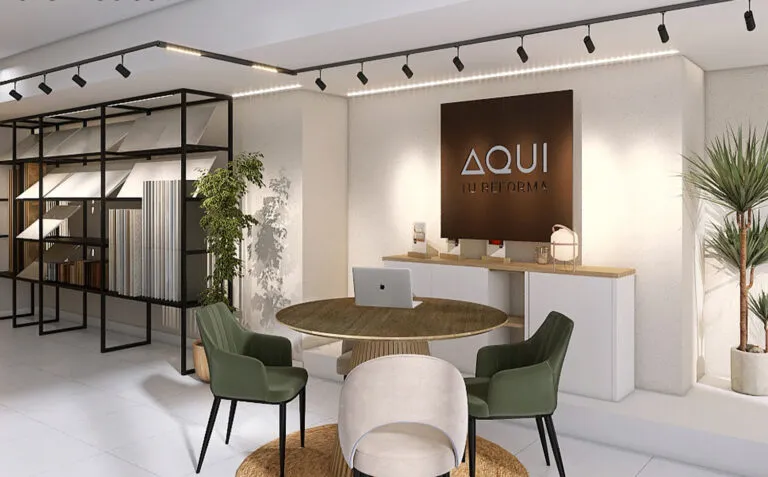 Moderna recepción de oficina con mesa redonda de madera, tres sillas verdes y una blanca, computadora portátil sobre la mesa, gabinetes blancos contra la pared, plantas de interior y un letrero iluminado que dice «AQUÍ REFORMA».