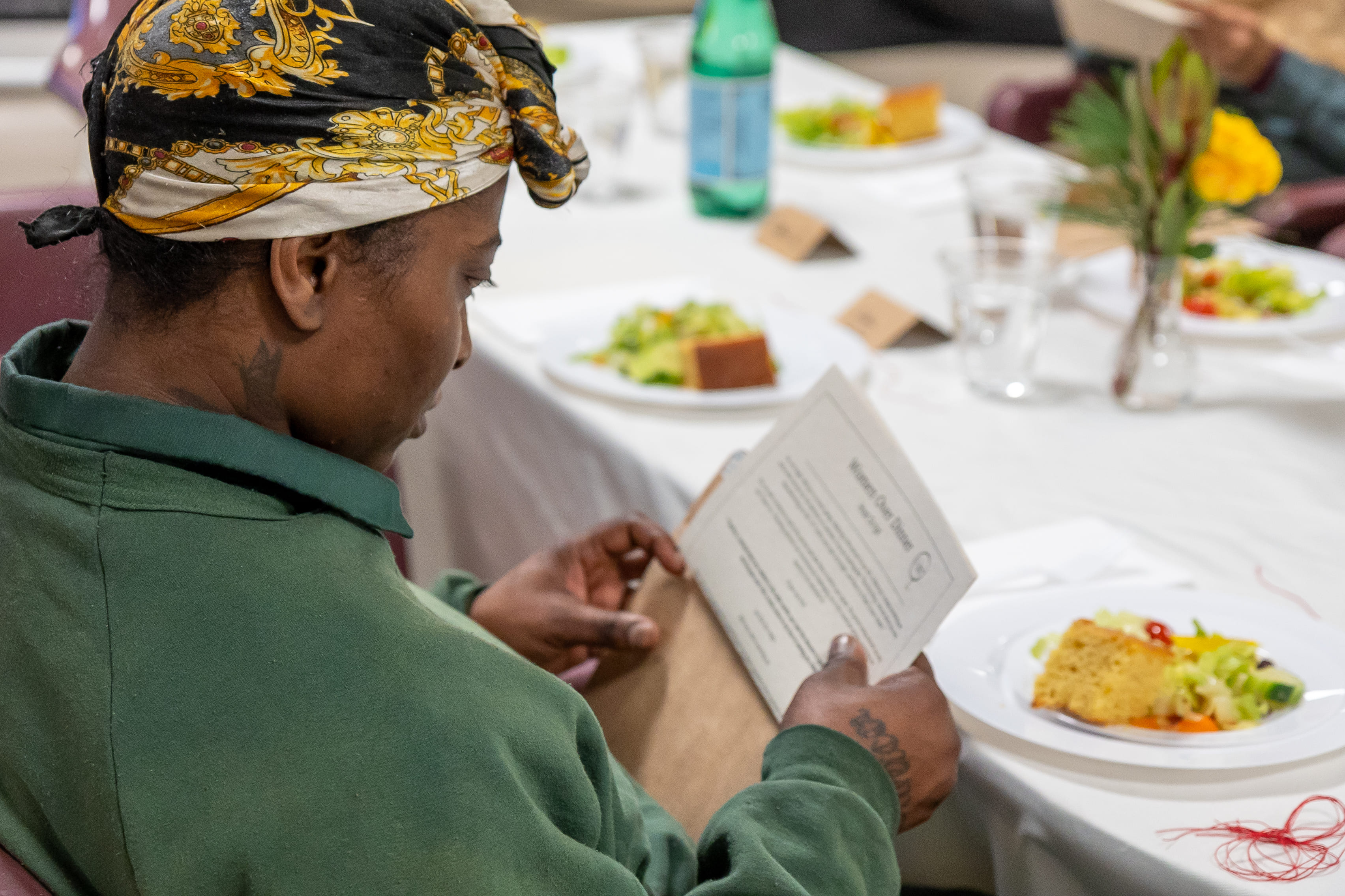 A woman reading the dinner program at her place setting.
