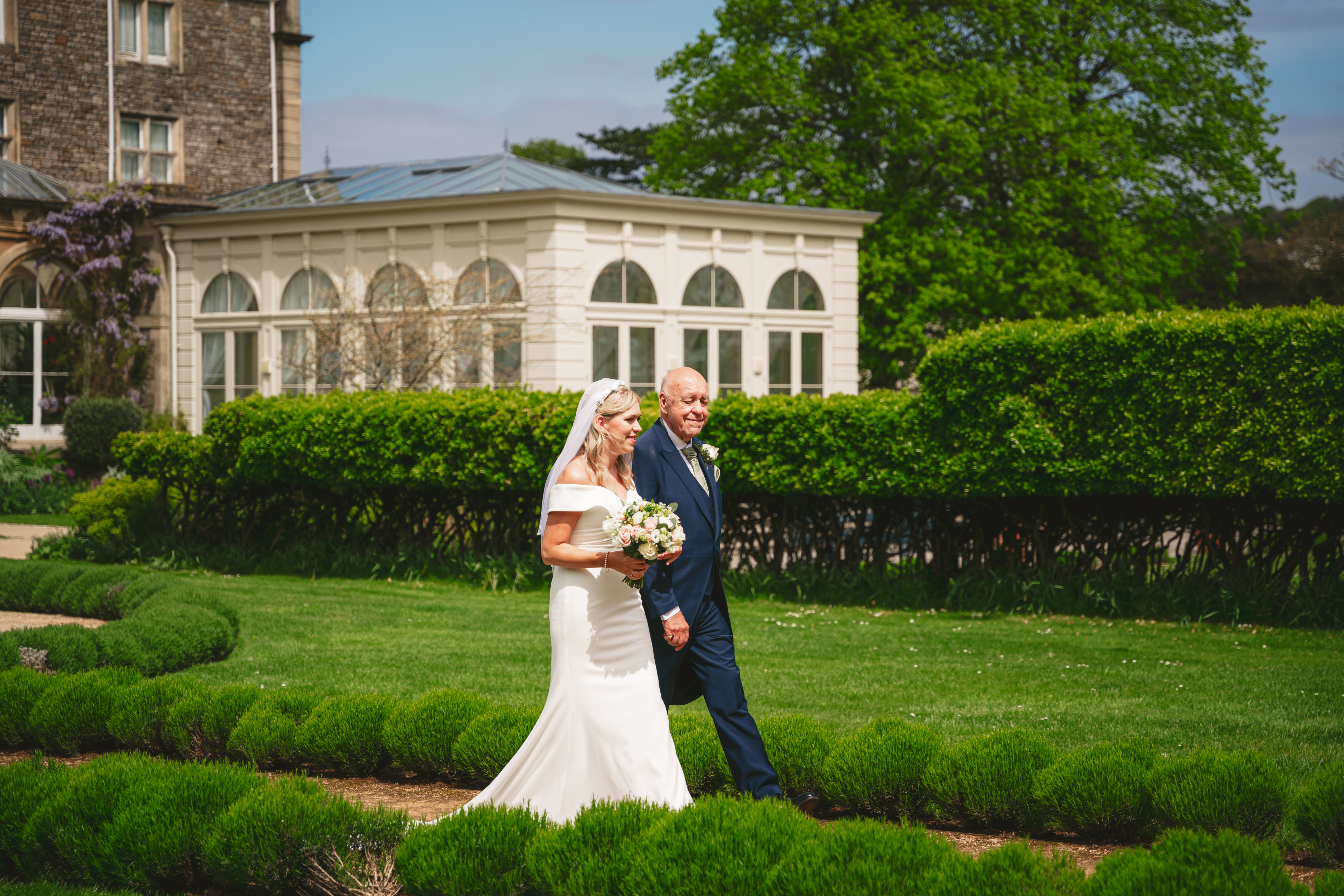 a groom and bride walking down a path